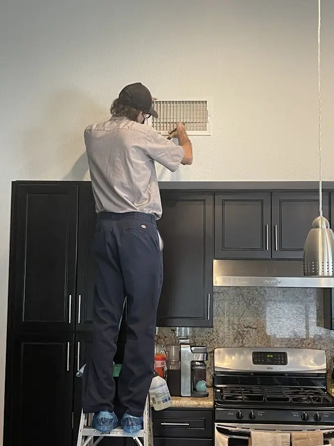 Technician inspecting an air vent during HVAC service in Brewton